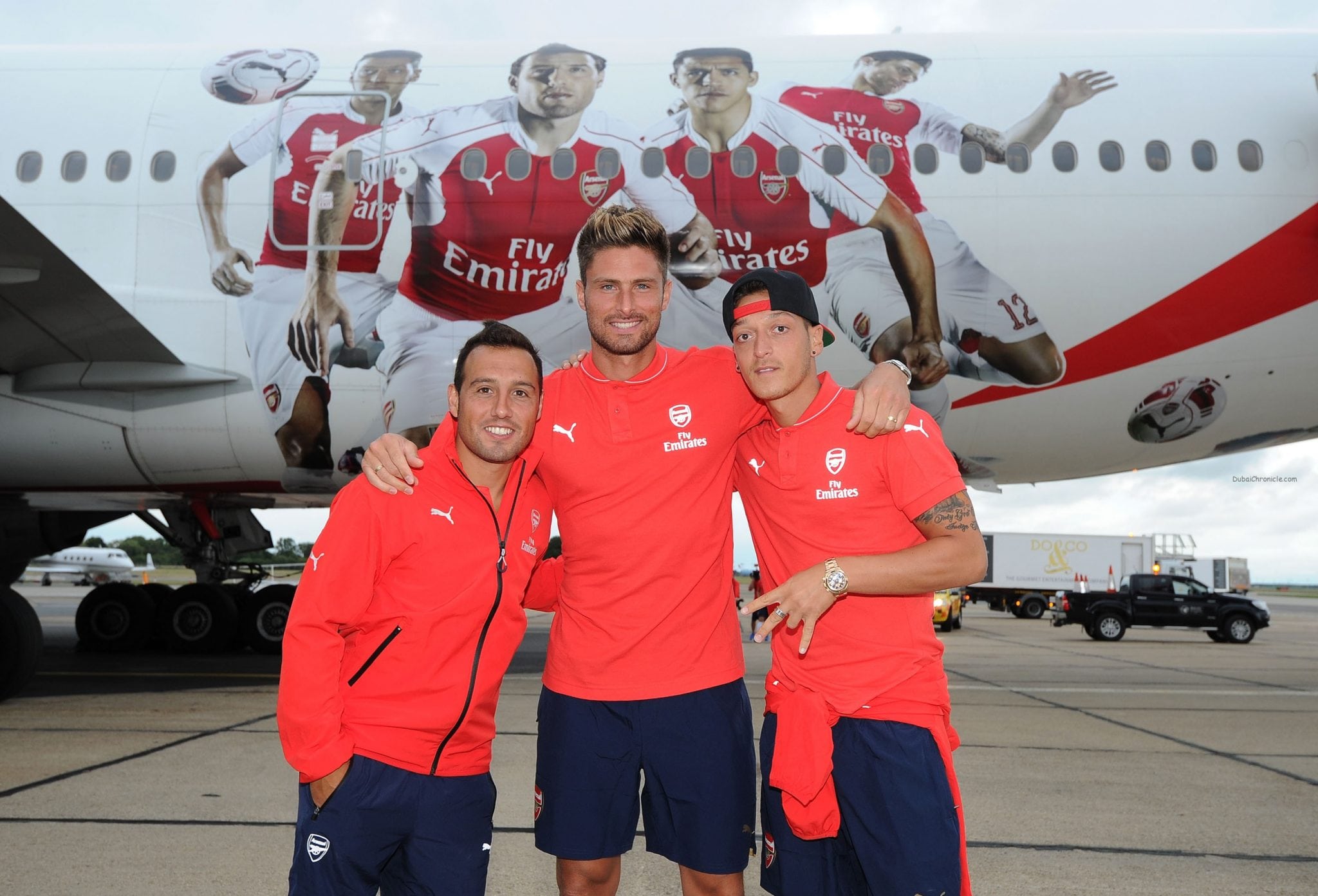 Santi Cazorla, Olivier Giroud and Mesut Ozil of Arsenal in front of their images on the Emirates plane at Stansted Airport on July 12, 2015 in London, England. (Photo by David Price/Arsenal FC via Getty Images) *** Local Caption *** Santi Cazorla; Olivier Giroud; Mesut Ozil